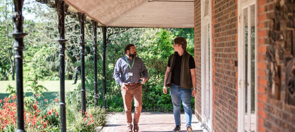 A student and worker talking to each other outdoors while walking on campus